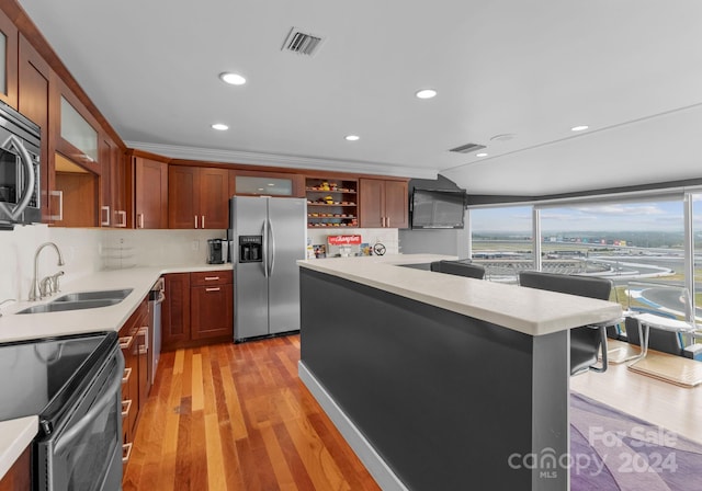 kitchen featuring sink, backsplash, appliances with stainless steel finishes, crown molding, and light hardwood / wood-style floors