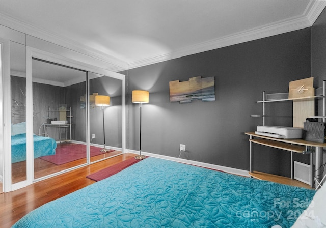 bedroom with crown molding, a closet, and hardwood / wood-style flooring