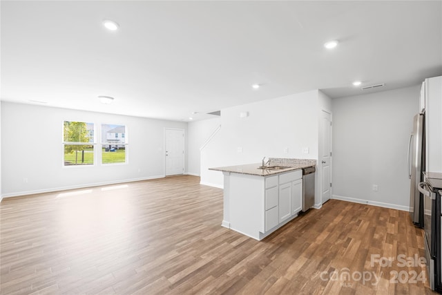 kitchen featuring light stone countertops, appliances with stainless steel finishes, light wood-type flooring, and white cabinetry