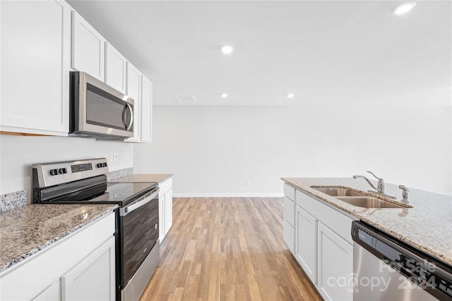 kitchen with white cabinets, light hardwood / wood-style floors, appliances with stainless steel finishes, and sink