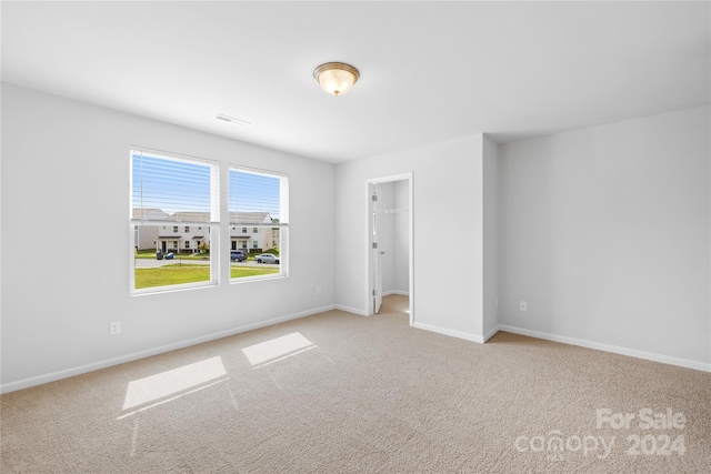 unfurnished bedroom featuring light carpet, a closet, and a spacious closet