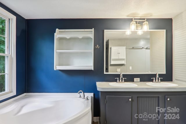 bathroom featuring vanity, a bathtub, a textured ceiling, and a healthy amount of sunlight