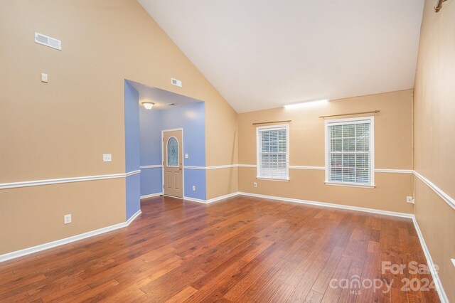 empty room featuring high vaulted ceiling and hardwood / wood-style flooring