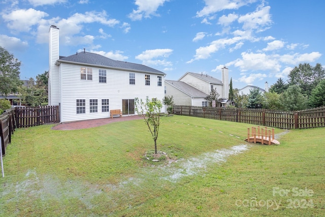 back of house with a yard and a patio