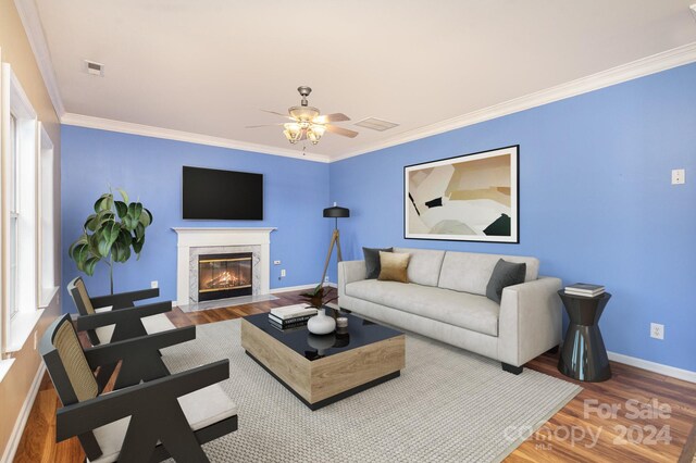 living room with crown molding, a fireplace, hardwood / wood-style floors, and ceiling fan