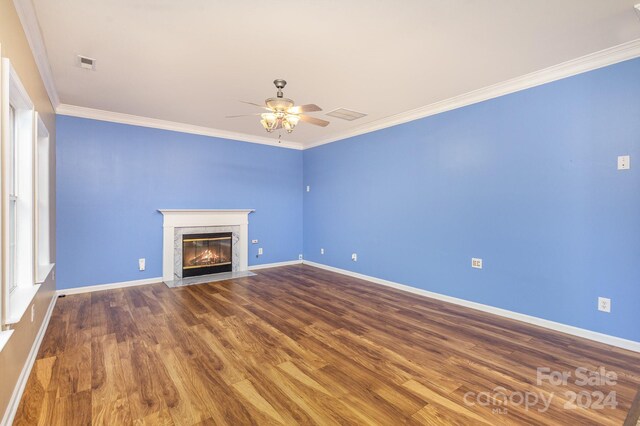 unfurnished living room with a fireplace, ornamental molding, ceiling fan, and hardwood / wood-style flooring