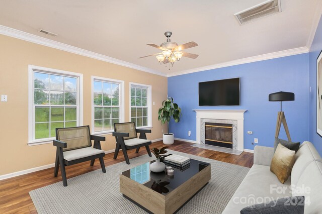 living room with ceiling fan, ornamental molding, a premium fireplace, and hardwood / wood-style floors