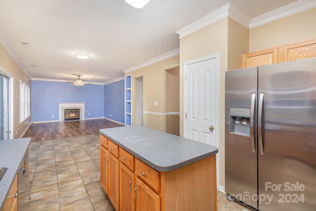 kitchen with stainless steel refrigerator with ice dispenser, a kitchen island, light hardwood / wood-style flooring, and ornamental molding