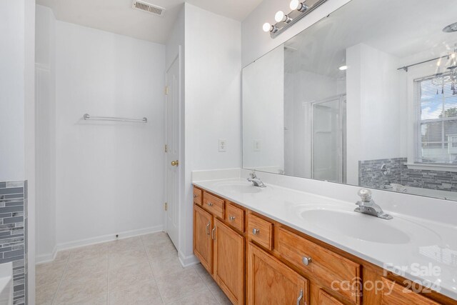 bathroom with a shower with shower door, vanity, and tile patterned floors