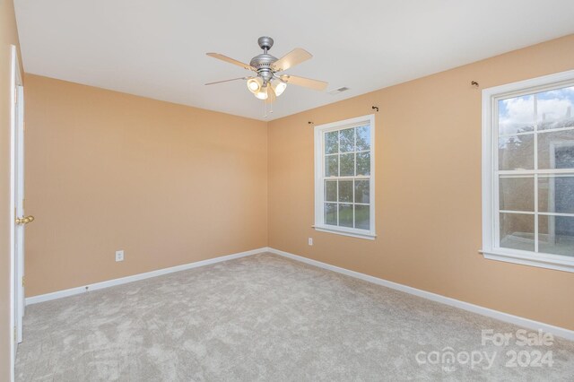 carpeted empty room featuring ceiling fan and a healthy amount of sunlight