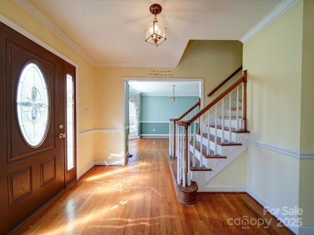 entryway featuring hardwood / wood-style flooring, crown molding, an inviting chandelier, and a textured ceiling