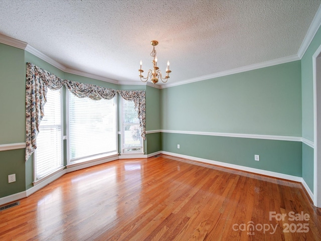 unfurnished room featuring crown molding, wood-type flooring, a chandelier, and a textured ceiling