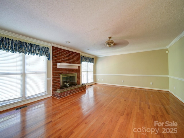 unfurnished living room with a fireplace, crown molding, wood-type flooring, and a textured ceiling