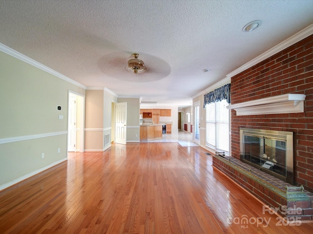 unfurnished living room featuring crown molding, light hardwood / wood-style floors, a brick fireplace, and a textured ceiling