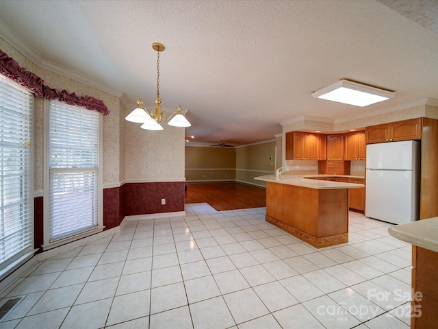 kitchen with ornamental molding, hanging light fixtures, white fridge, and a textured ceiling