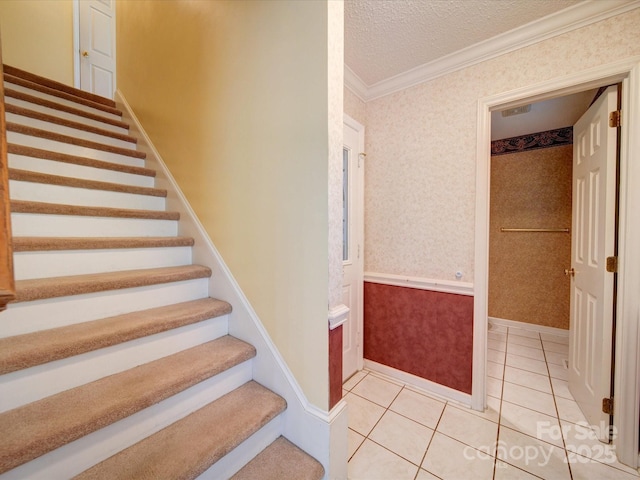 stairway with crown molding, tile patterned floors, and a textured ceiling