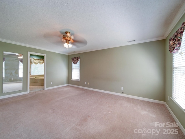 carpeted spare room featuring crown molding, a wealth of natural light, ceiling fan, and a textured ceiling