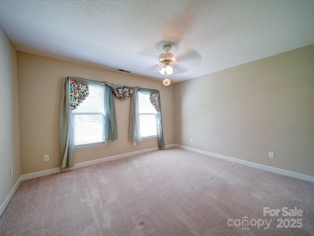 spare room with ceiling fan, light carpet, and a textured ceiling