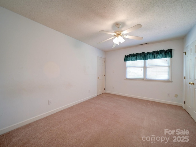 carpeted empty room with ceiling fan and a textured ceiling