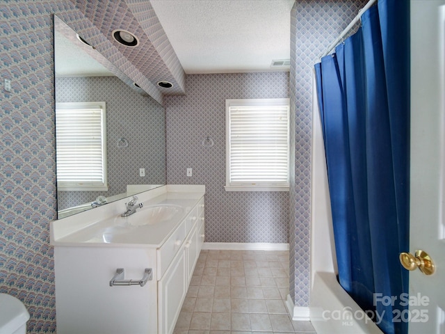 bathroom with vanity, plenty of natural light, tile patterned floors, and a textured ceiling