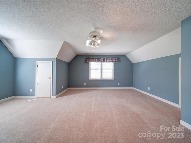 bonus room featuring vaulted ceiling, light carpet, a textured ceiling, and ceiling fan