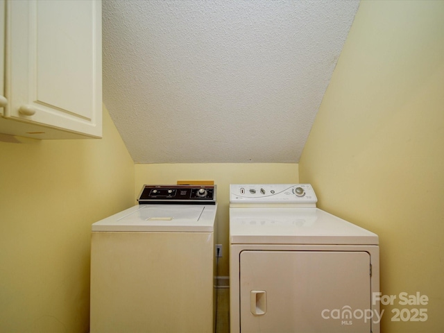 laundry room with cabinets, a textured ceiling, and washing machine and clothes dryer