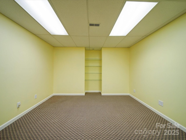 carpeted empty room with a drop ceiling