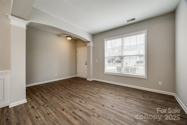 unfurnished room with dark hardwood / wood-style floors and ornate columns