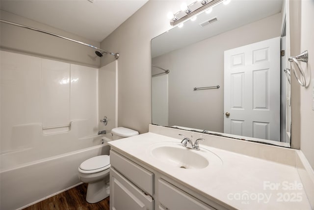 full bathroom with hardwood / wood-style flooring, washtub / shower combination, vanity, and toilet