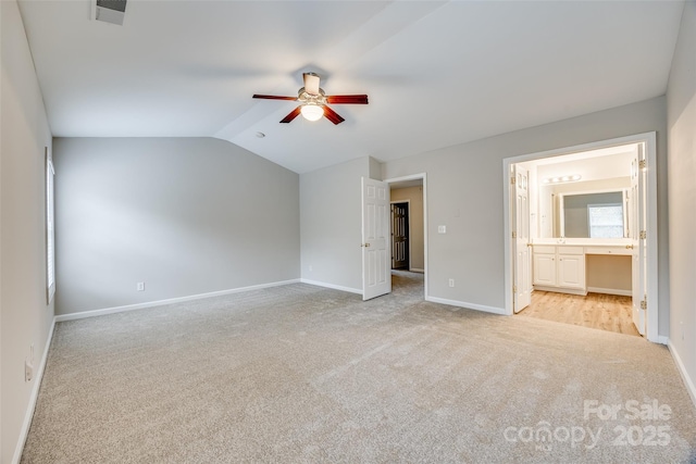 unfurnished bedroom with ceiling fan, light colored carpet, lofted ceiling, and connected bathroom