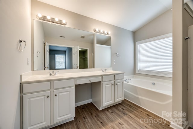 bathroom featuring hardwood / wood-style flooring, vanity, lofted ceiling, and a bathtub