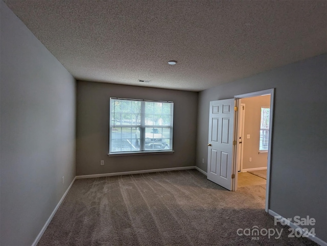 empty room with a textured ceiling and carpet flooring