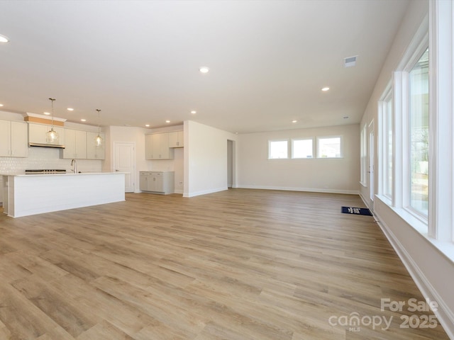 unfurnished living room with recessed lighting, light wood-type flooring, and a sink