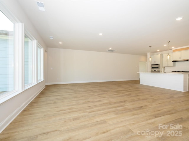 unfurnished living room with recessed lighting, plenty of natural light, and light wood finished floors