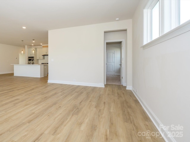 unfurnished living room featuring recessed lighting, baseboards, and light wood finished floors