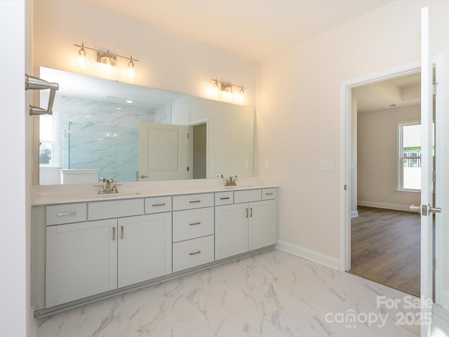 bathroom featuring a marble finish shower, marble finish floor, double vanity, and a sink