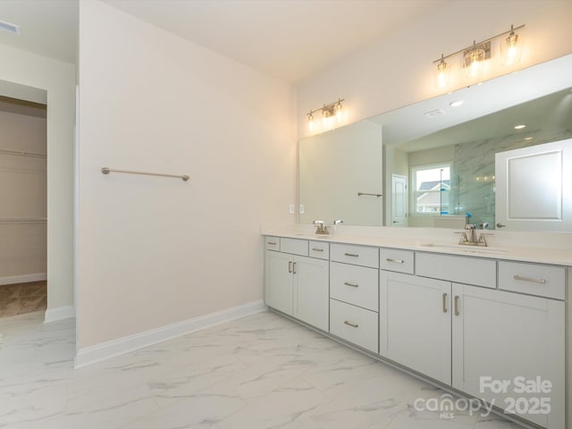 full bathroom with a marble finish shower, baseboards, double vanity, marble finish floor, and a sink