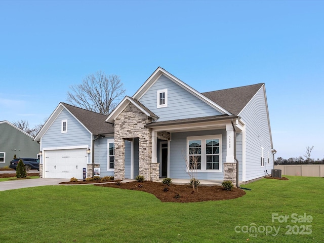 craftsman-style home featuring a front lawn, driveway, stone siding, roof with shingles, and a garage