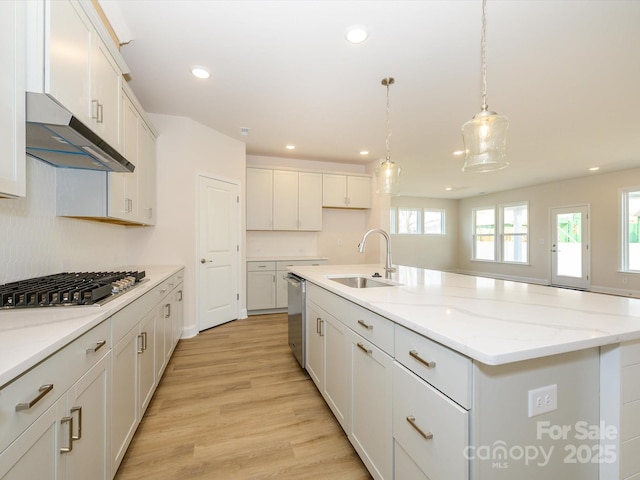 kitchen with a sink, appliances with stainless steel finishes, under cabinet range hood, recessed lighting, and a center island with sink