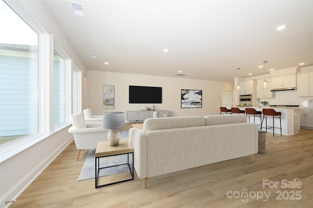 living area featuring visible vents, baseboards, light wood-type flooring, and recessed lighting