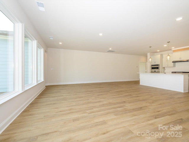 unfurnished living room with a wealth of natural light, light wood finished floors, and recessed lighting
