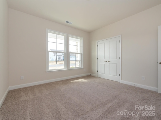 unfurnished bedroom featuring a closet, visible vents, baseboards, and carpet floors