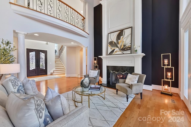 living room featuring a fireplace, light hardwood / wood-style floors, and a high ceiling