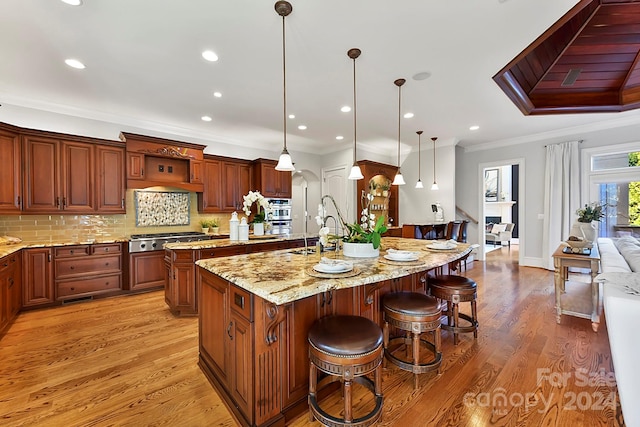 kitchen with ornamental molding, hanging light fixtures, hardwood / wood-style flooring, and a spacious island