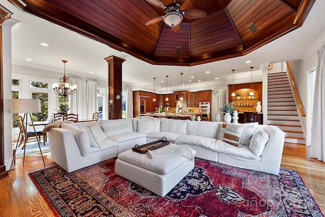 living room featuring wood ceiling, light hardwood / wood-style floors, ceiling fan with notable chandelier, crown molding, and ornate columns