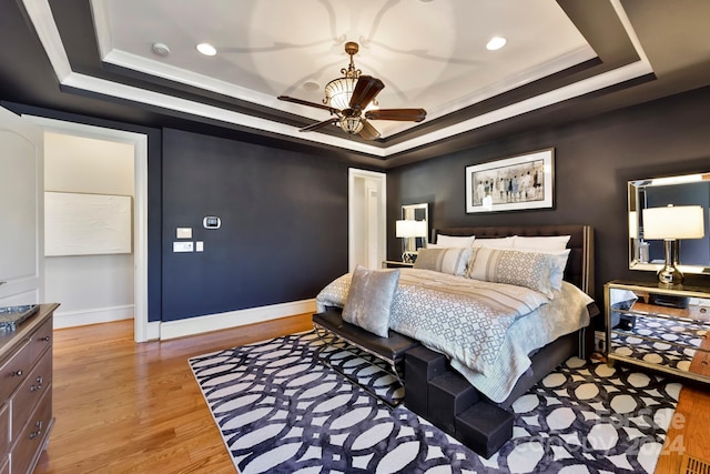 bedroom with a raised ceiling, light hardwood / wood-style floors, and ceiling fan