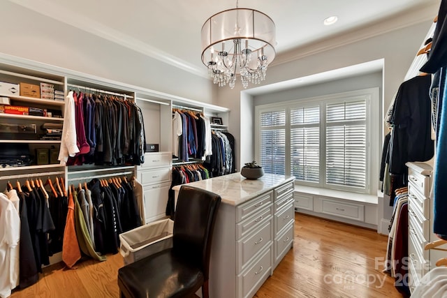 walk in closet featuring an inviting chandelier and light hardwood / wood-style floors