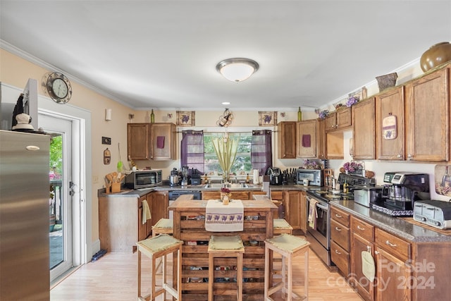 kitchen featuring light hardwood / wood-style flooring, ornamental molding, appliances with stainless steel finishes, and a healthy amount of sunlight