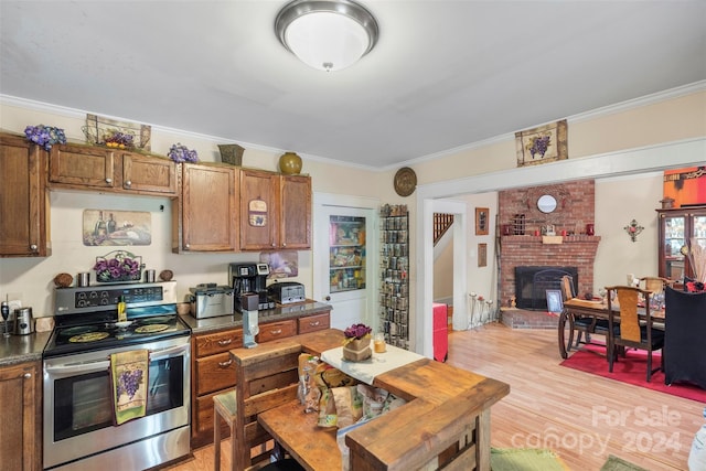 kitchen featuring light hardwood / wood-style flooring, a brick fireplace, electric stove, and crown molding