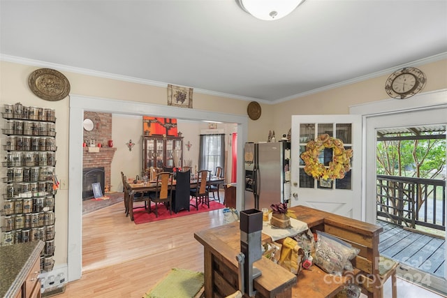 dining room featuring ornamental molding, a brick fireplace, and light hardwood / wood-style floors